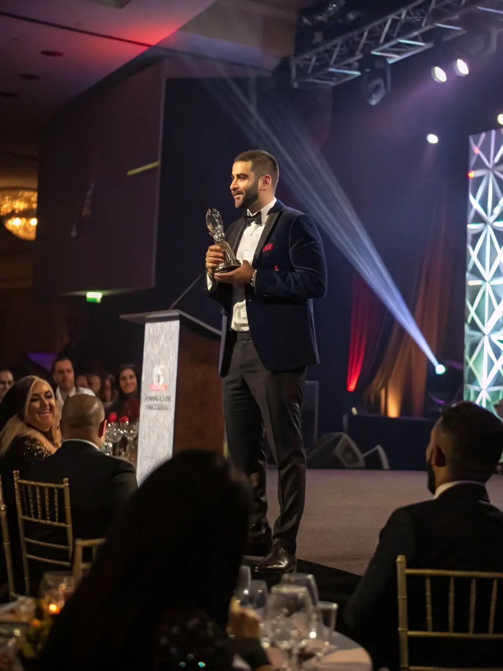 An Indian entrepreneur receiving an award on stage, symbolizing success and recognition, with a supportive audience in the background.